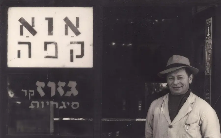 צילום ארכיון בשחור לבן: איש בכובע עומד מתחת לשלט 'אוא קפה'